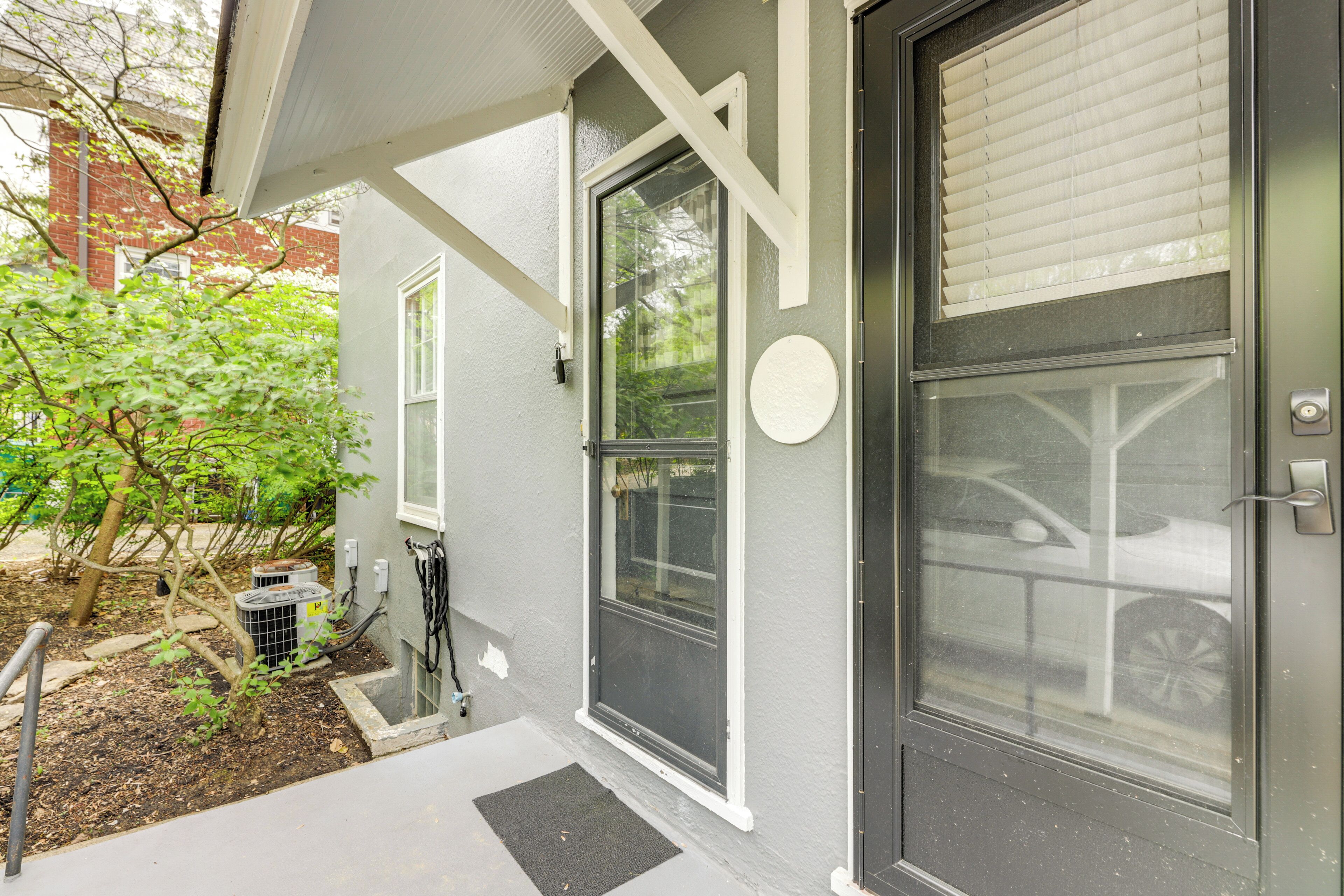 A residential building with a grey exterior, large windows, and a door with a black frame.