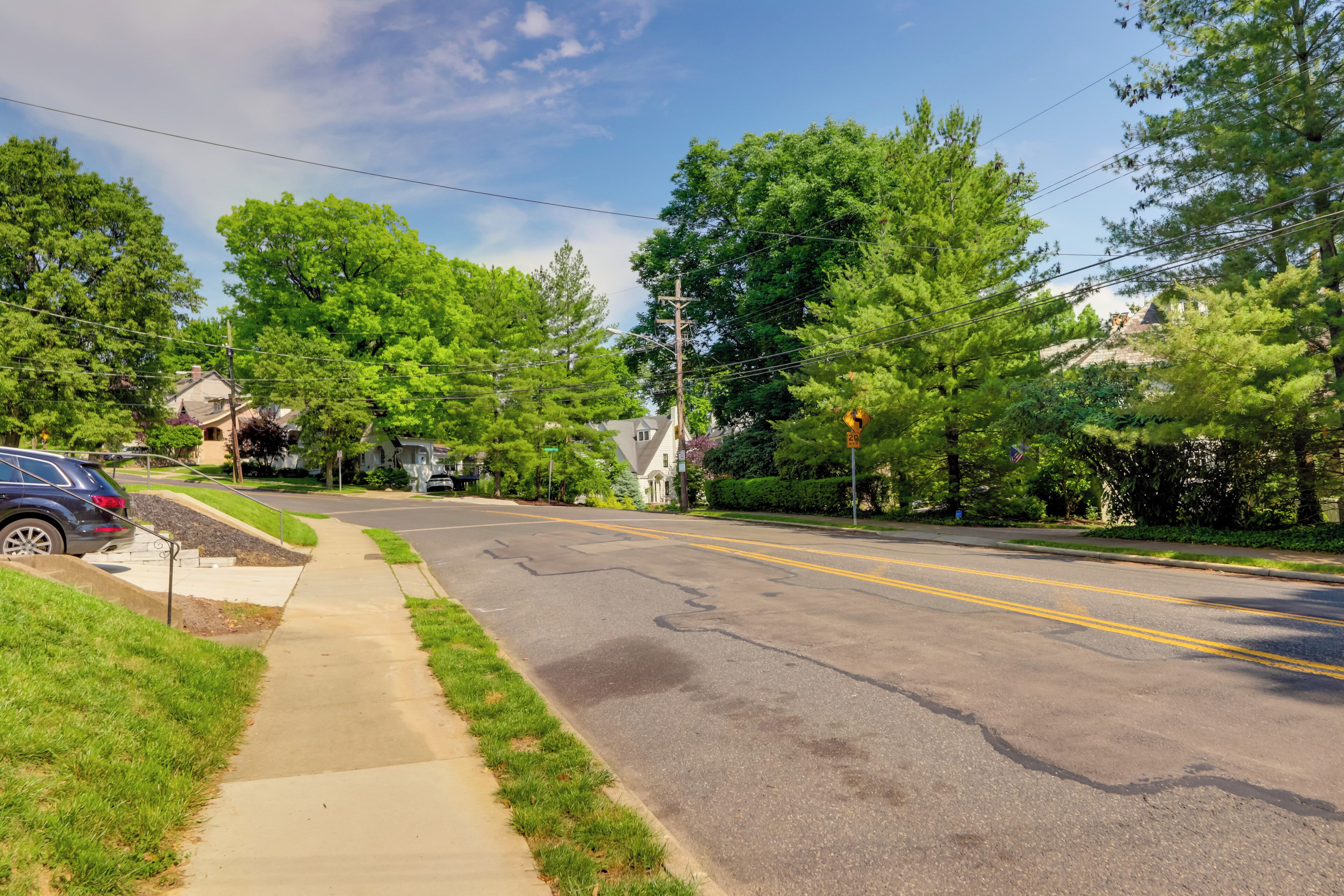 A suburban street with houses, a sidewalk, and a road.