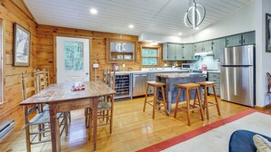 Una cocina moderna con paredes de madera, electrodomésticos de acero inoxidable y una isla central con taburetes.