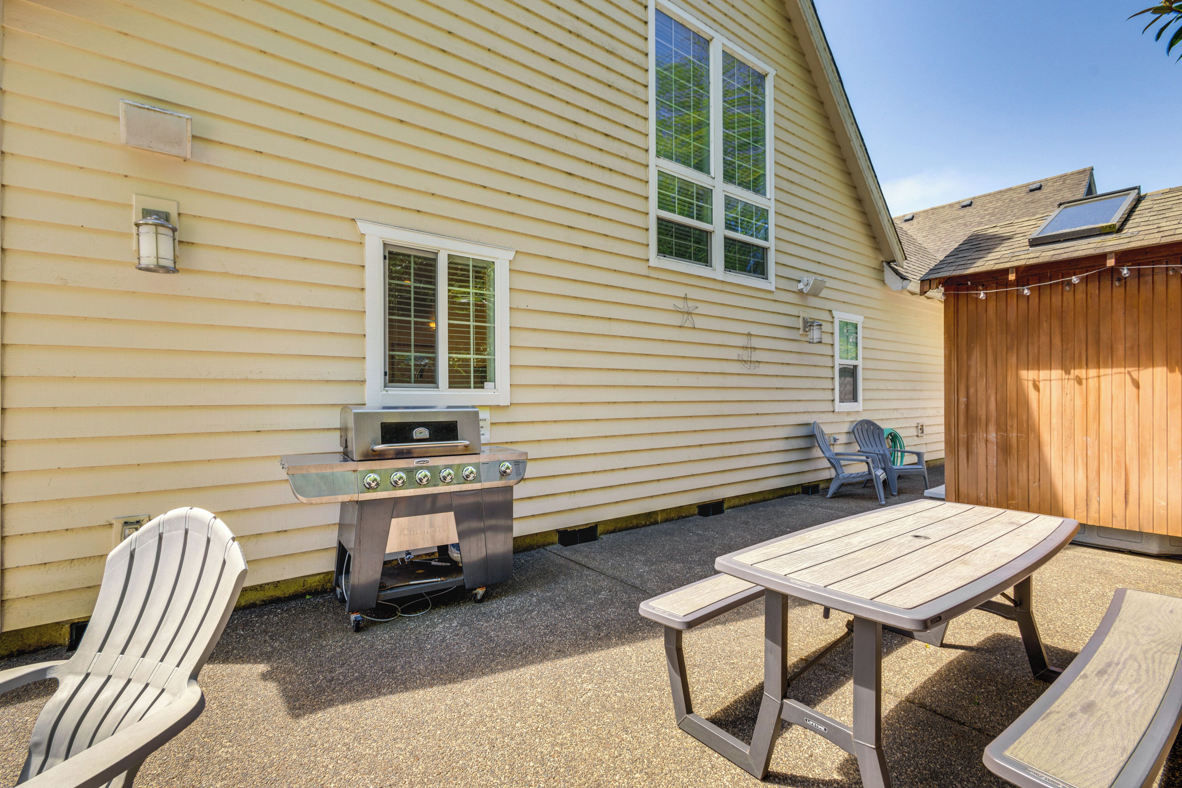 A backyard with a grill, two Adirondack chairs, and a picnic table.