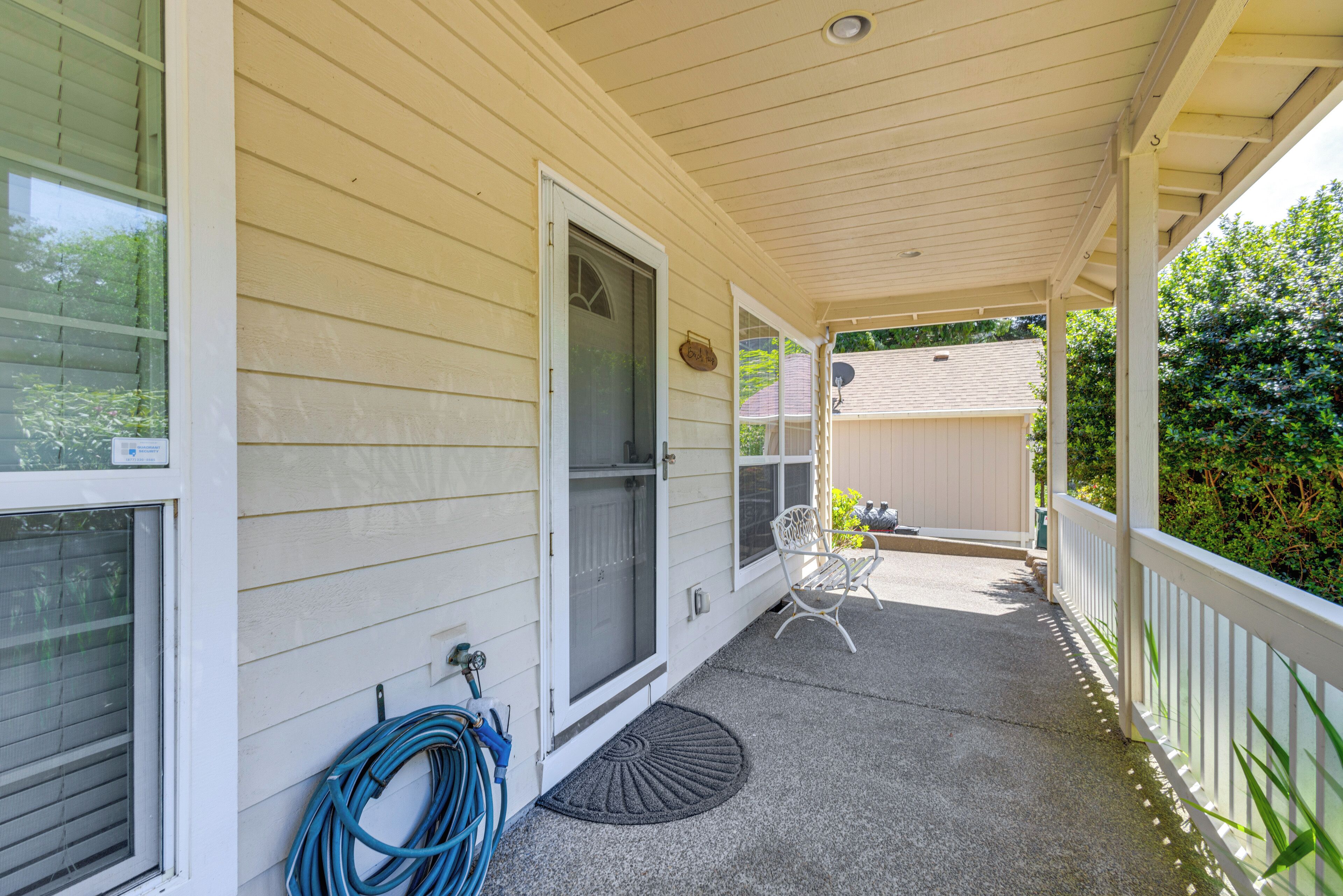 A covered porch with a door, a chair, and a doormat.