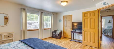 Un dormitorio con cama, una silla, un escritorio y una puerta que da a otra habitación.