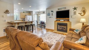 Una sala de estar con chimenea, televisor y una zona de cocina con barra.