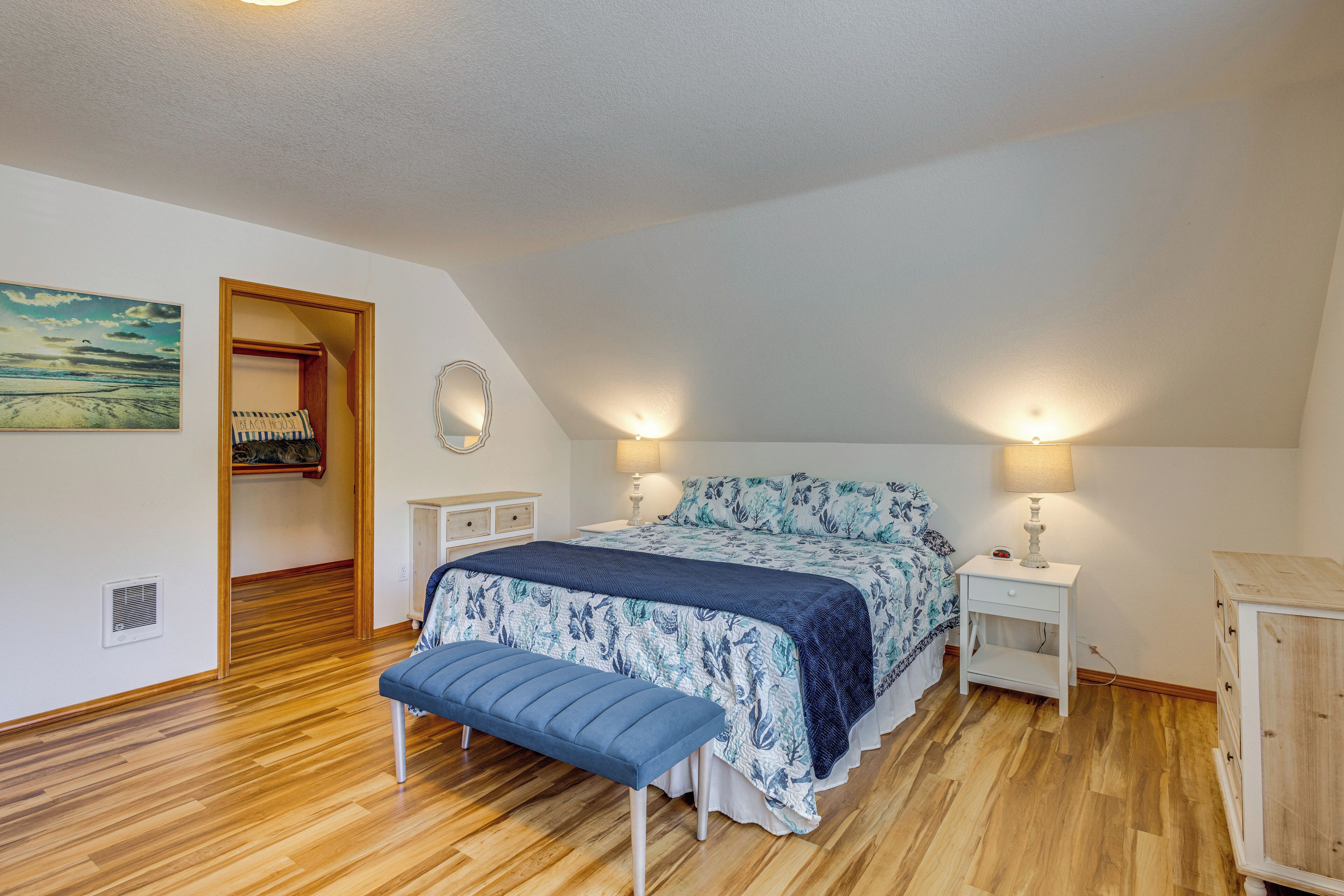 A bedroom with a bed, bedside tables, a bench, a wardrobe, and a painting on the wall.