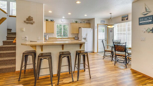 Una cocina moderna con una isla central, taburetes de bar y una zona de comedor con mesa y sillas.