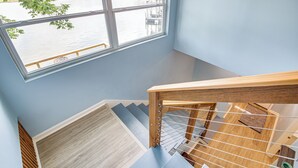 A wooden staircase with a view of a river through a large window. - Waterfront Lake Hamilton Vacation Rental w/ Dock! (Royal)