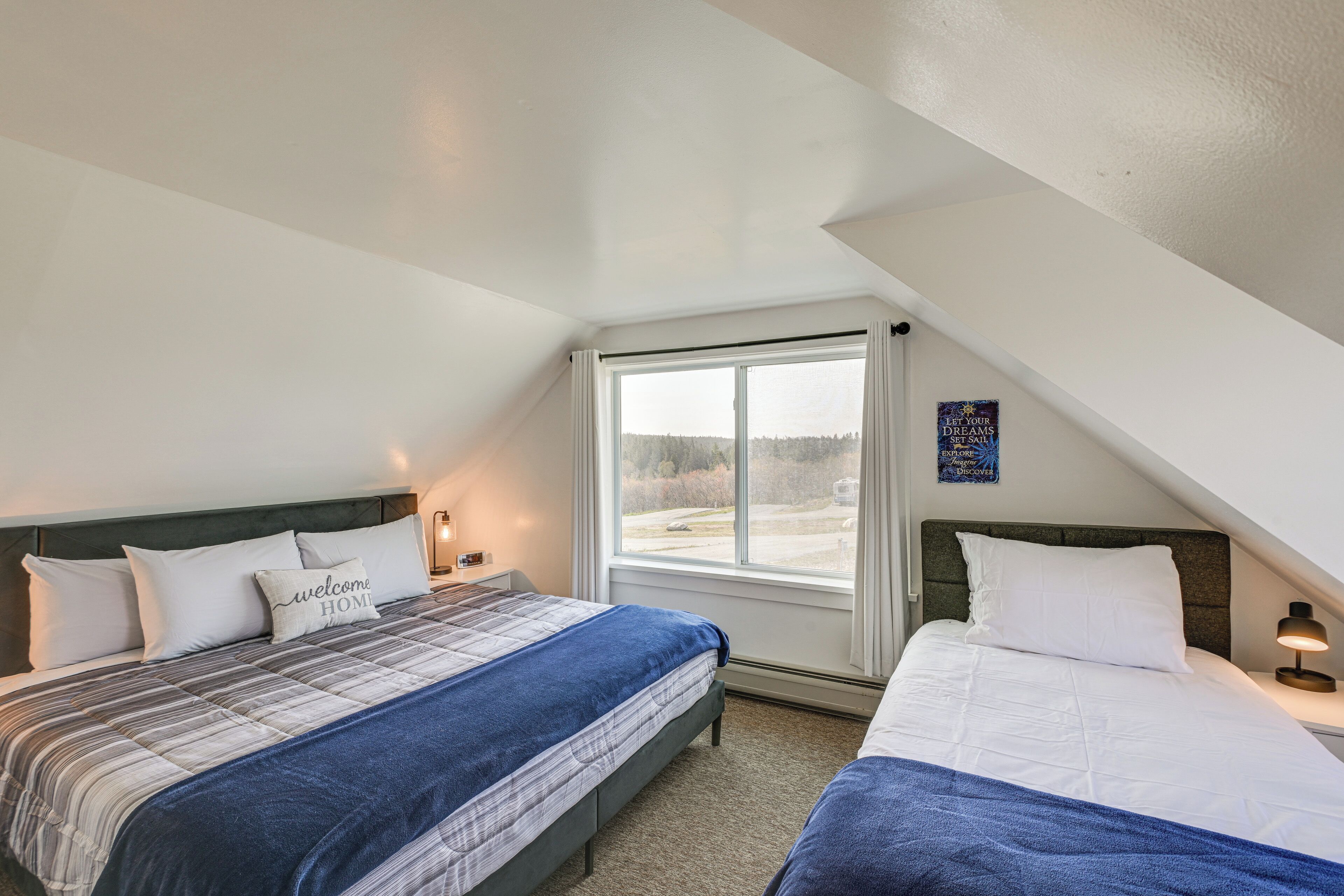 Une chambre avec deux lits, une fenêtre et un luminaire fixé au mur.