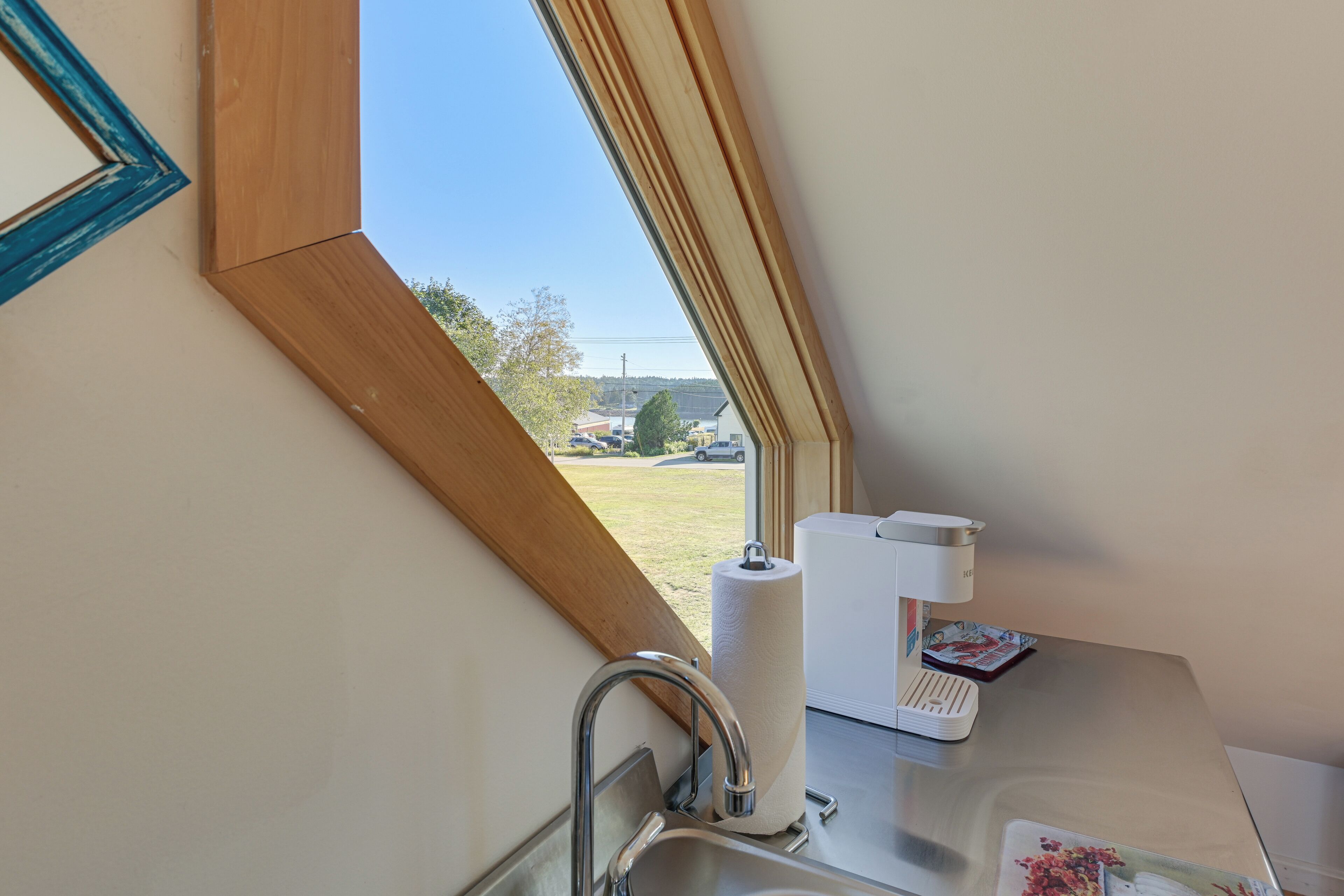 A bathroom with a window, a towel dispenser, and a toilet paper holder.
