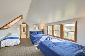 A bedroom with two beds, a skylight, a large window, and a door leading to another room. - Prime Coastal Location! Spacious Family Villa (Winter Harbor)
