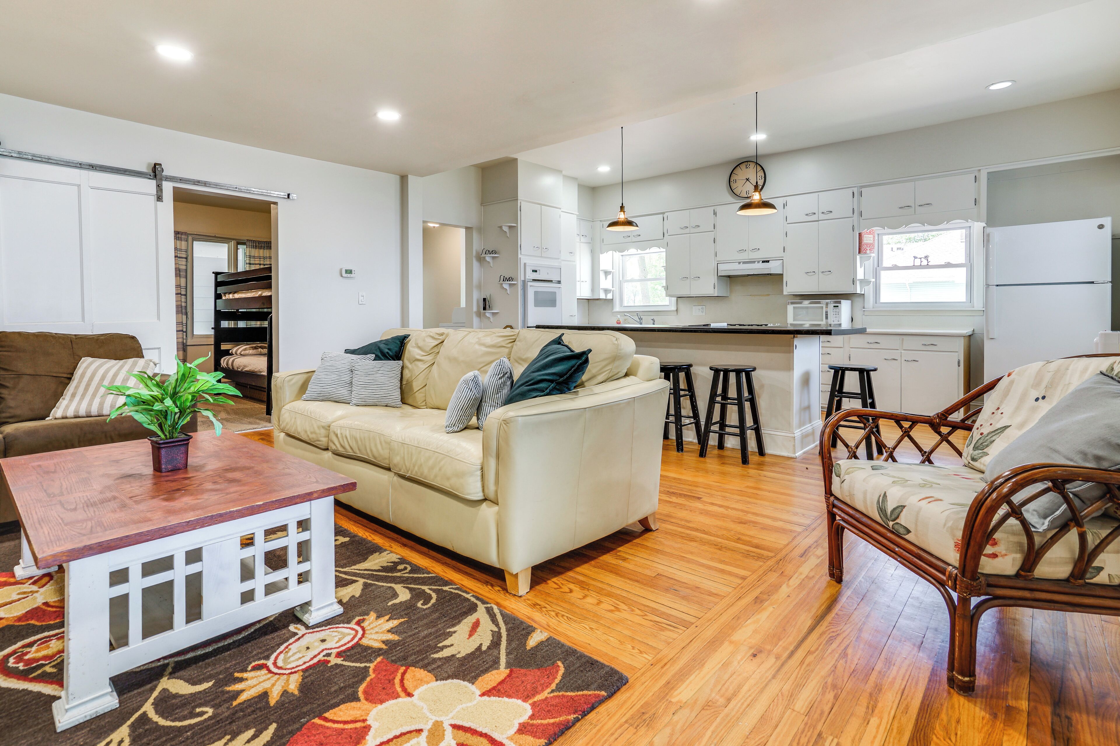A modern living room with a sofa, a coffee table, and a dining area with stools.