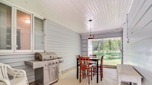 A covered outdoor kitchen with a grill, oven, and dining table with chairs. - Lakeside Litchfield Home w/ Patio & Gas Grill! (Litchfield)