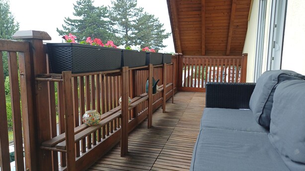 Une terrasse en bois avec un canapé et des jardinières fleuries.