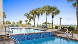 A swimming pool with blue mosaic tiles, surrounded by palm trees and lounge chairs. - Panoramic Sunset Views, Beachfront (Panama City Beach)
