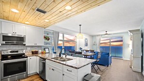 A modern kitchen with white cabinets, stainless steel appliances, and a wooden ceiling. - Panoramic Sunset Views, Beachfront (Panama City Beach)