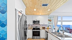 A modern kitchen with white cabinets, stainless steel appliances, and a wooden ceiling. - Panoramic Sunset Views, Beachfront (Panama City Beach)
