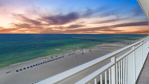 A beach with a pier extending into the ocean, a white railing, and a clear sky. - Panoramic Sunset Views, Beachfront (Panama City Beach)