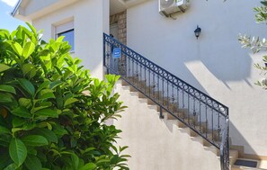 Stairs lead to an apartment entrance surrounded by lush greenery.