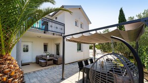 A covered patio area with a seating arrangement, a hanging chair, and a view of a building with a balcony. - Gorgeous home in Polaca (Polaca)