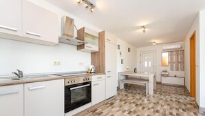 A modern kitchen with white cabinets, a black oven, and a wooden countertop. There is a dining table with chairs and a small kitchen island. - Gorgeous home in Polaca (Polaca)