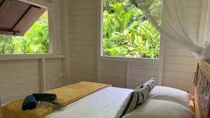 A single bed with a yellow blanket, white pillows, and a dark blue towel. - Cottage in the heart of the rainforest  (Sainte-Rose)