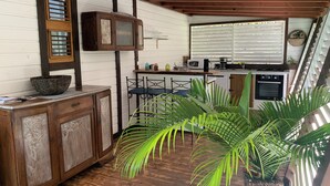 A kitchen with wooden cabinets, a microwave, and a sink. There is a large potted plant in the center. - Cottage in the heart of the rainforest  (Sainte-Rose)