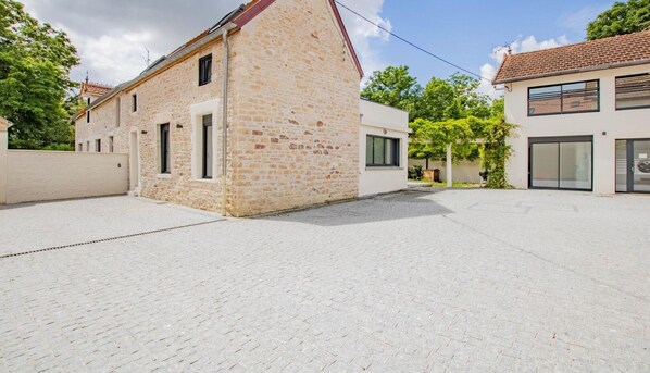 A courtyard with a stone building and a modern house. - Le Clos Napoléon - MELLECEY (MELLECEY)
