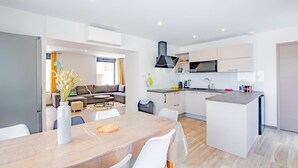 A modern kitchen with white cabinets, a central island, and a dining area with a table and chairs.