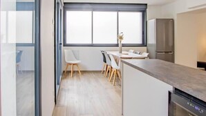 A modern kitchen with a built-in dishwasher, a large window, and a dining area with a table and chairs.