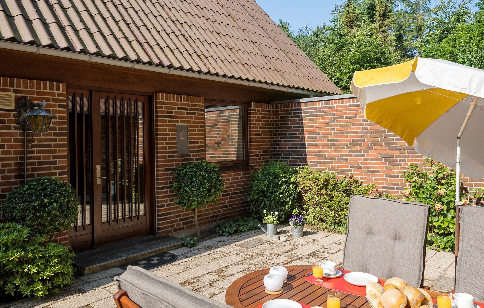 A brick house with a tiled roof, a wooden door, and a small patio area with a table set for breakfast.