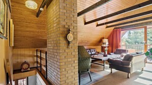 Ein gemütliches Wohnzimmer mit Kamin aus Ziegelsteinen, Holzbalken, einer Ledersofa und einem Essbereich mit Tisch und Stühlen.