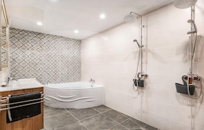A modern bathroom with a freestanding bathtub, a shower with a handheld showerhead, and a towel rack with towels.