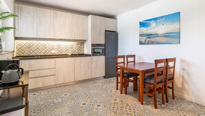 A compact kitchen with wooden cabinets, a built-in oven, and a refrigerator. There's a dining table with four chairs and a patterned floor. - Stunning home in Vélez-Málaga (Vélez-Málaga)