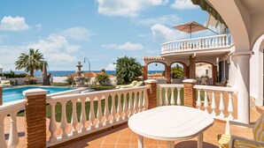 A poolside area with a white balustrade, a round table, and a chair. - Stunning home in Vélez-Málaga (Vélez-Málaga)