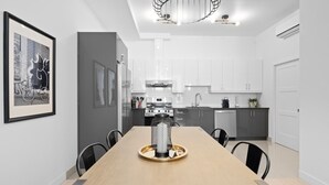 A modern kitchen with white cabinets, a dining table with chairs, and a chandelier. - New Modern 2bdr Apartment in Little Italy (Montréal)