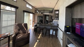 A spacious living area with a large window, a ceiling fan, and a kitchen area with a bar counter. - WALK TO INDIAN RIVER MARINA AT NORRIS LAKE
Book now! Memorial Weekend available (Jacksboro)
