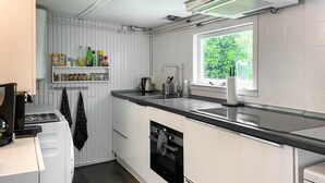 A compact kitchen with white cabinets, a black countertop, a built-in oven, and a window providing natural light. - Stunning (sta)caravan in Reeuwijk (Reeuwijk)
