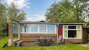 A rustic cabin with a large glass window, wooden walls, and a small porch area. - Stunning (sta)caravan in Reeuwijk (Reeuwijk)