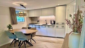 Une cuisine moderne avec des meubles de couleur bois clair, un îlot central et un coin repas comprenant une table et des chaises en bois.