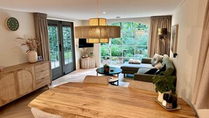Un salon moderne avec une table à manger en bois, un canapé et une grande fenêtre donnant sur un paysage verdoyant.