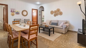 A living room with a dining area, a sofa, a coffee table, and a TV. - Gorgeous apartment in Malaga with house sea view (Malaga)