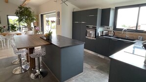 Una cocina moderna con armarios oscuros, una isla central y una zona de comedor con taburetes de bar.