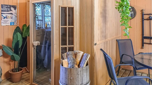 A wooden interior with a glass door, a potted plant, a chair, and a table. - Amazing home in Sävsjö with kitchen (Sävsjö)