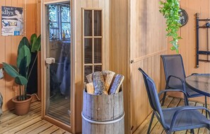 Un interior de madera con una puerta de vidrio, una planta en maceta, una silla y una mesa.