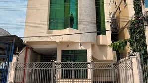 A modern building with a large glass facade, a gated entrance, and a visible satellite dish. - Mini Suite Equipada Frente al Aeropuerto! (Guayaquil)