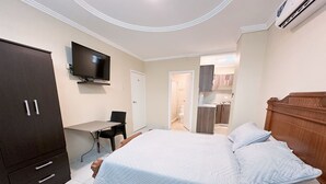 A bedroom with a bed, a desk, and a TV. - Mini Suite Equipada Frente al Aeropuerto! (Guayaquil)