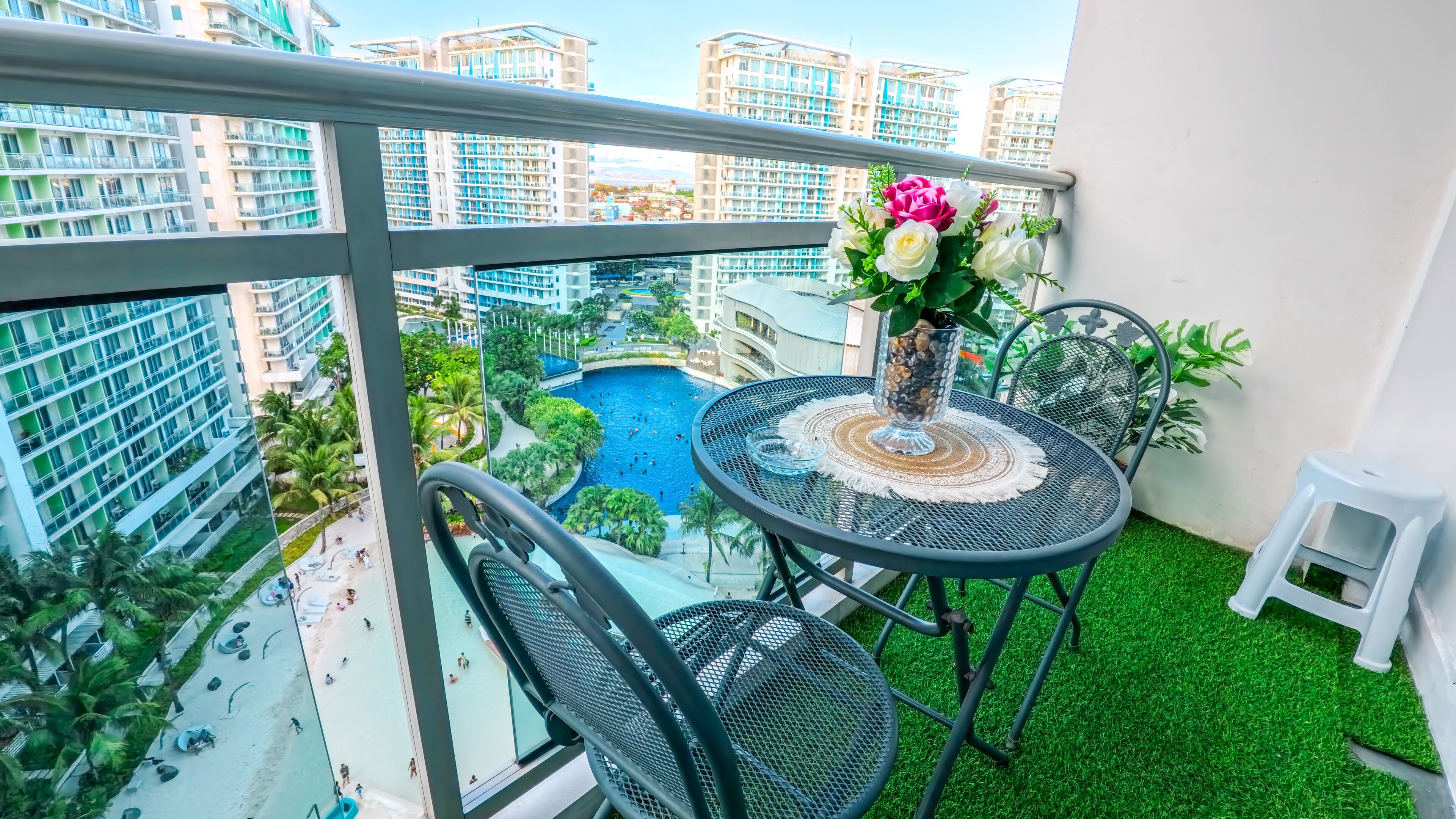 Un balcon avec une table ronde, des chaises et un vase de fleurs.