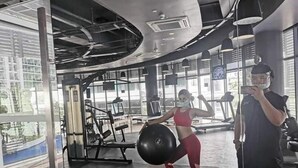 A gym with exercise equipment, large windows, and a person lifting weights. - Stunning 1-bed Apartment in Paranaque (Parañaque)