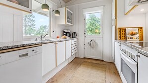 Een moderne keuken met witte kastjes, een granieten werkblad, een inbouwvaatwasser en een raam voor natuurlijk licht.