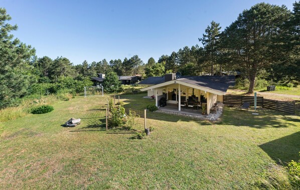 Une maison avec un patio couvert, une cour clôturée et un poteau de but de football.