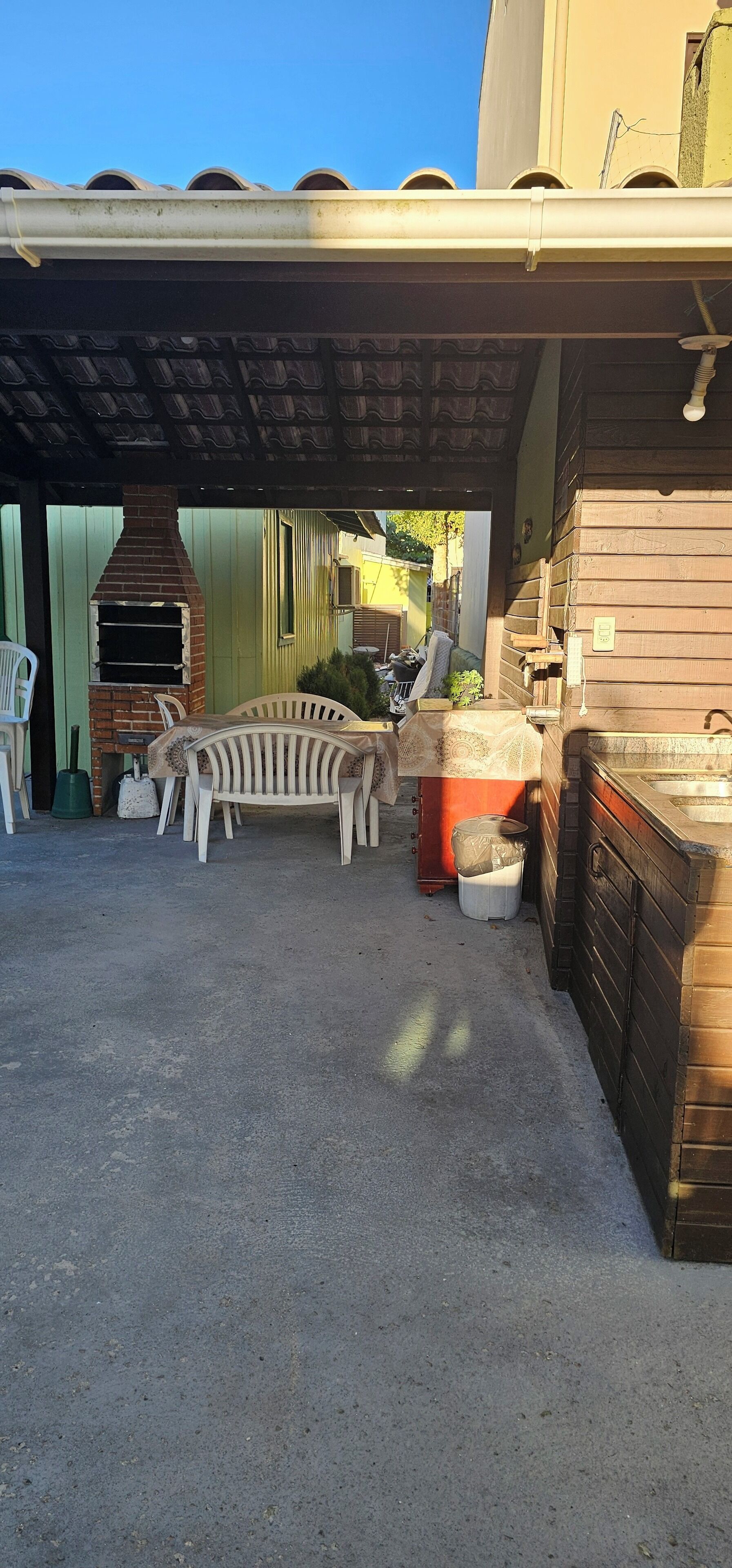 An outdoor patio area with a brick oven, a wooden table, and a bench.